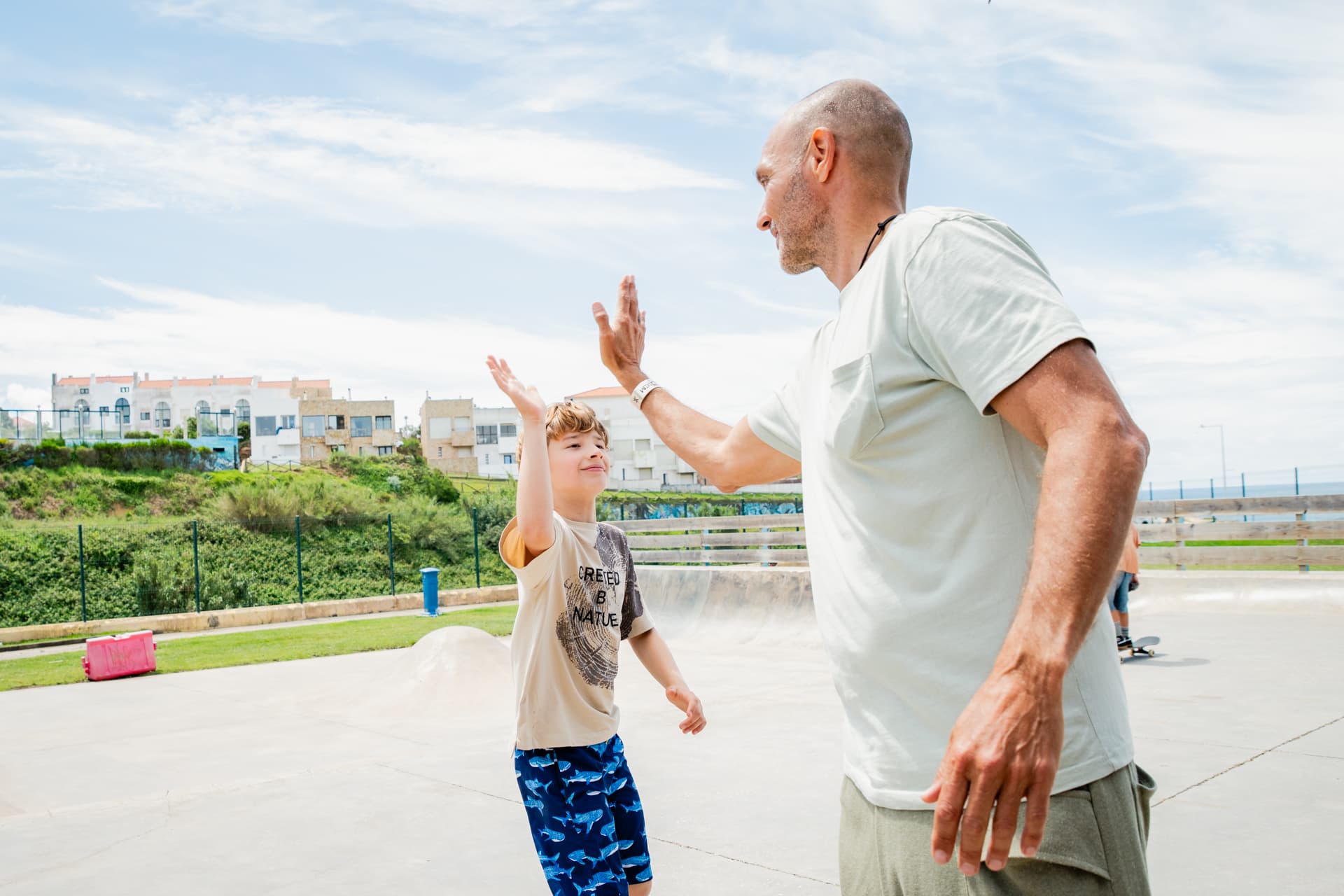 Un coach fait un check à un garçon souriant au skatepark