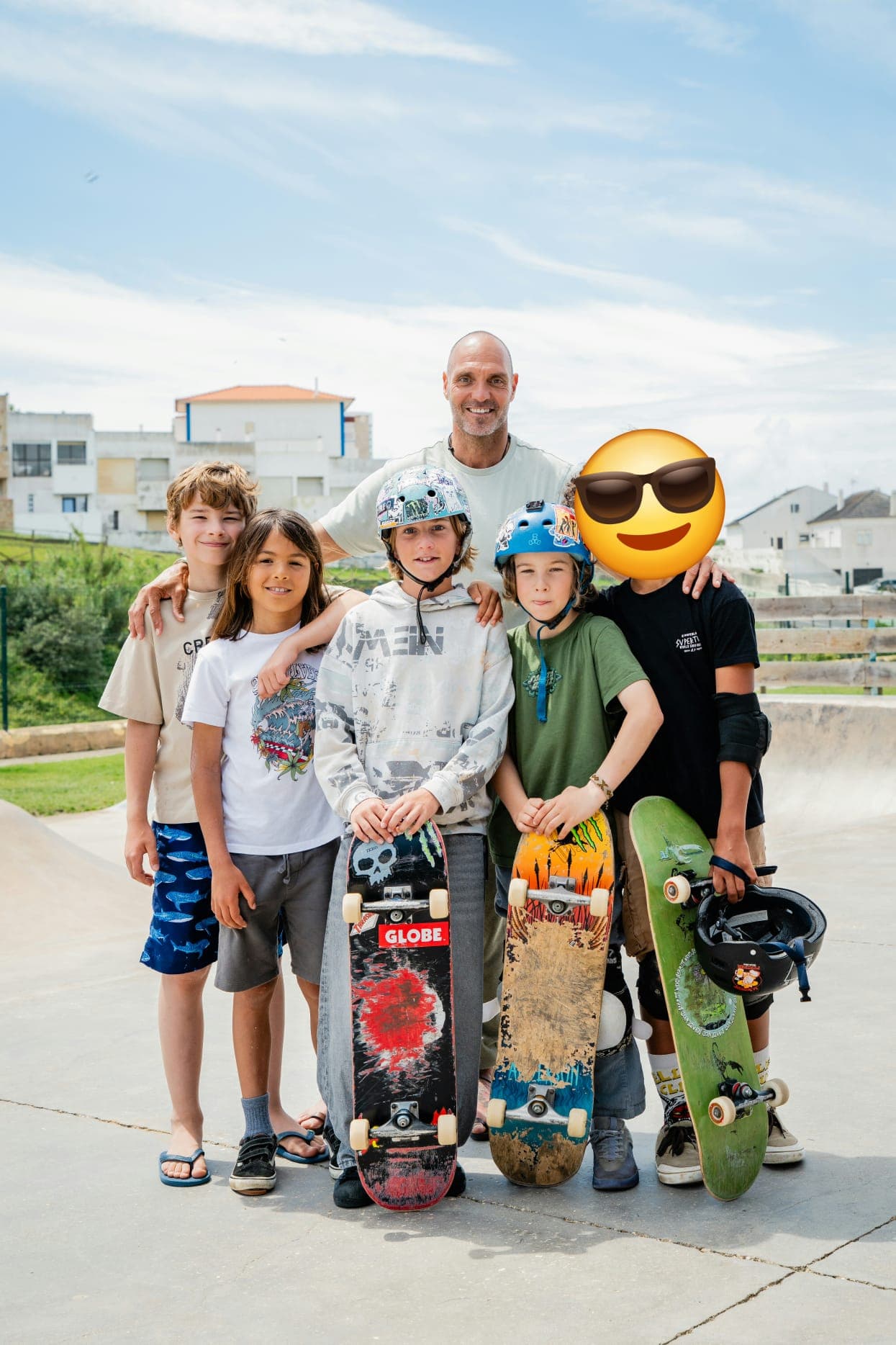 Un monitor junto a cinco chicos que sostienen sus monopatines en el skatepark